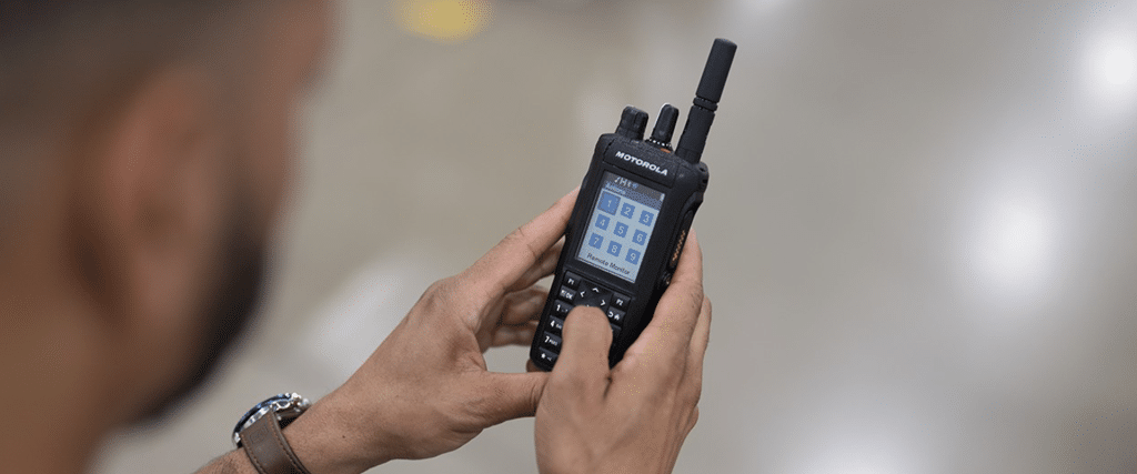 A manufacturing employee using the work-ticketing function on a Motorola two-way radio. The radio has a keypad and full color display.